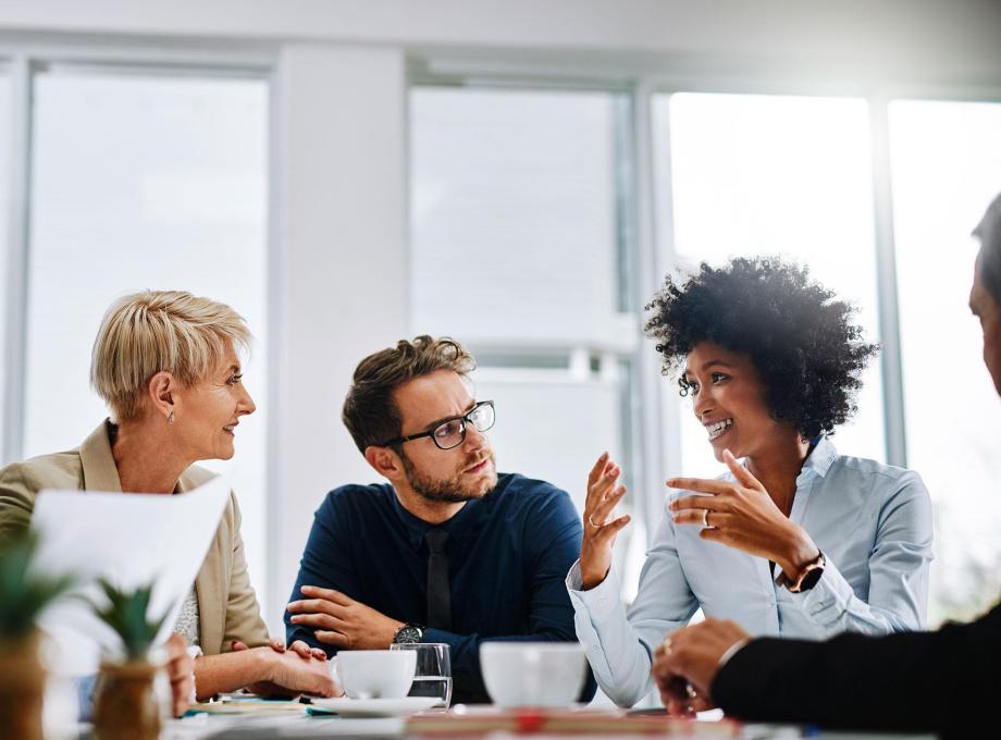 Discussion collaborative entre collègues dans un bureau lumineux, illustrant le travail d’équipe et la communication professionnelle