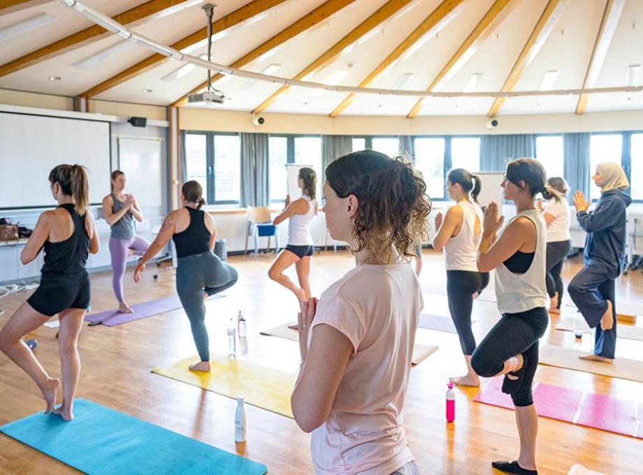 Groupe de personnes pratiquant le yoga dans une salle ensoleillée.